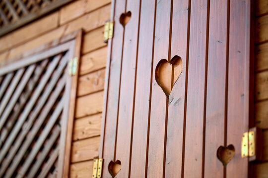 Wooden shutters with heart cutouts on rustic cabin