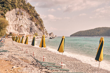 Spiaggia di Skopelos con ombrelloni chiusi mossi dal vento in una giornata estiva tranquilla