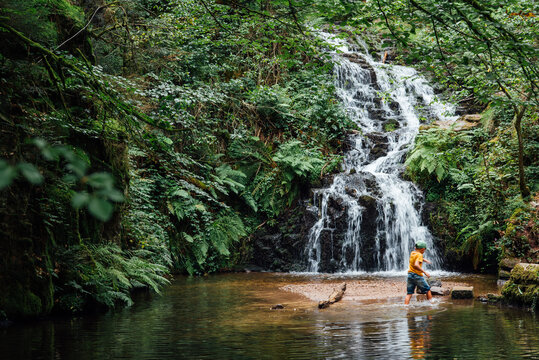 un enfant jouant vers une cascade d'eau. Chute d'eau &agrave; la cascade de Faymont. 
Enfant s'amusant dans l'eau en pleine for&ecirc;t durant l'&eacute;t&eacute; caniculaire.