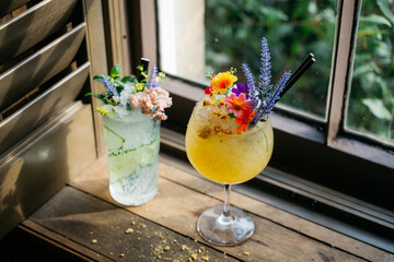 Two drinks with flowers on top sit on a table next to each other