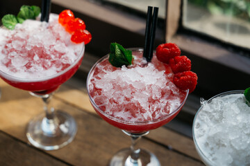 Three martini glasses with a garnish of raspberries and ice