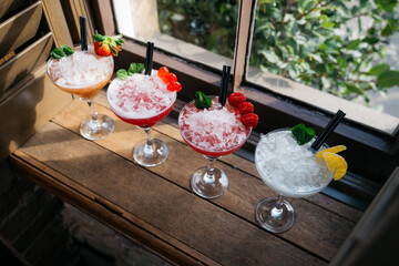 Four different cocktails in martini glasses with ice and garnishes