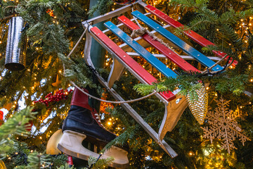 Children's sleds for downhill skiing and ice skates decorate the Christmas tree. Soviet-era sleds and children's skates on the Christmas tree. Festive decoration on Christmas Eve in retro style.