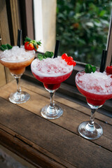 Three martinis with different garnishes and one with a strawberry on top