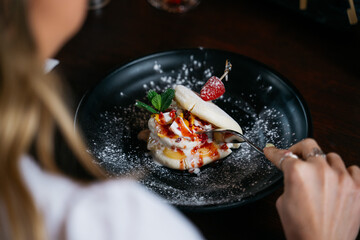 A woman is eating a dessert with a fork