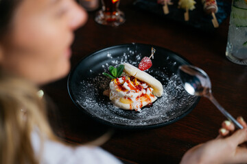 A woman is eating a dessert with a spoon