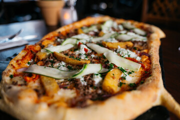 A large pizza with a variety of toppings including cucumbers and cheese