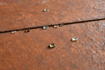Close-up of water droplets on a rusted metal surface with a crack