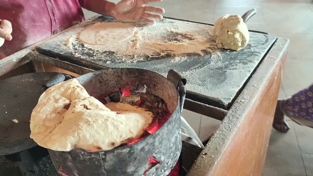 An women making Jowar roti with hand and baking it over a hot charcoal 