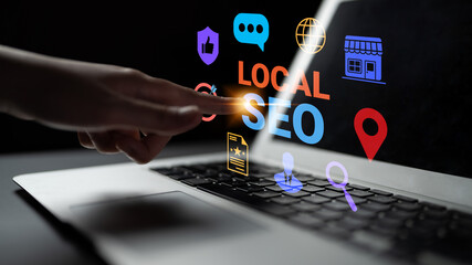 A close-up image of a hand touching a laptop screen displaying colorful icons representing local SEO, highlighting digital marketing strategies for businesses aiming for online growth. Gantry
