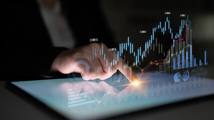 A professional using a tablet to analyze market trends, featuring interactive graphs and data visualizations for financial insights in a dark setting. Scalp