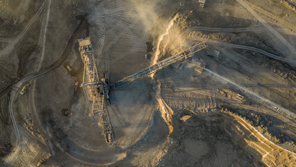 Aerial view of an active coal mining site showcases heavy machinery and smoke billowing into the air