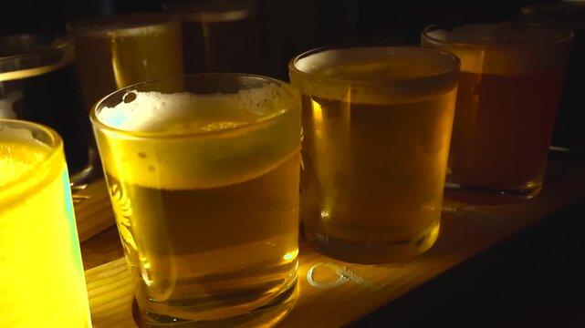 Close up of glowing craft beer sampler glasses on a wooden tray in a dim Lisbon bar with foam, bubbles, and shallow depth of field