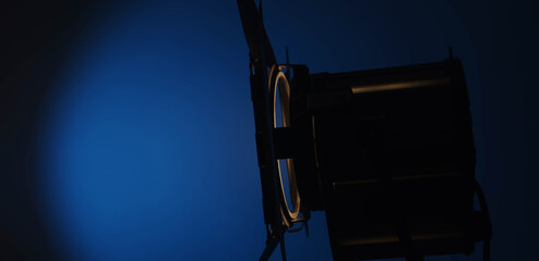 A warm orange studio spotlight is turned on with a blue gradient in the background, using cinematic lighting. Lighting equipment backstage.
