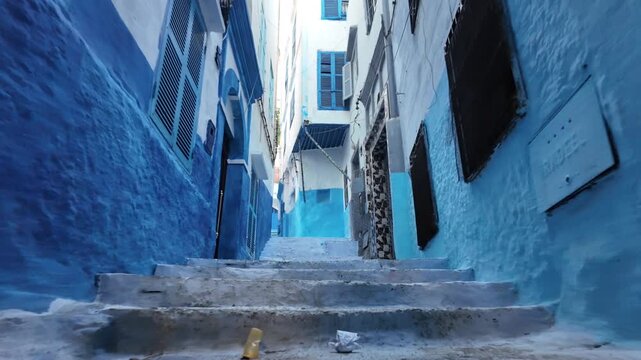 Chefchaouen blue city alley with traditional moroccan architecture and vibrant painted walls, narrow old medina street featuring steep steps and windows, travel destination cultural heritage