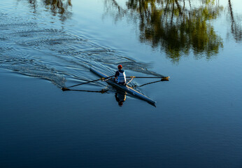  a rower leaves circles on the surface of the blue water of a lake. © ninika