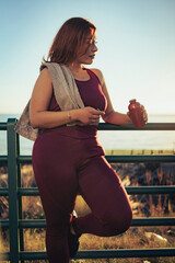 Tired athlete resting holding reusable water bottle and towel after workout