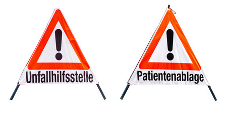 Two triangular warning signs with large exclamation marks and the texts "unfallhilfsstelle" and "patientenablage", foldable stands with reflective fabric, clear view of typography and graphics.