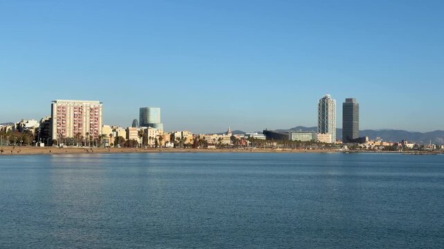 Wide shot of Barcelona city skyline along the Mediterranean coast, tranquil sea, clear sky and modern architecture, travel destination background with large copy space