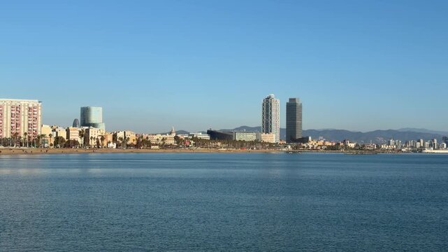 Barcelona waterfront skyline with calm Mediterranean sea, modern urban coastline and clear blue sky, panoramic travel background with copy space and peaceful city atmosphere