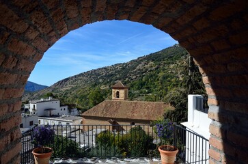 Iglesia de la Santa Cruz en Pampaneira a trav&eacute;s de un arco, Alpujarra de Granada, Andaluc&iacute;a, Espa&ntilde;a
