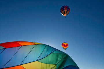 Hot air balloons, Two flying into a dark blue sky while one is being inflated on the ground.