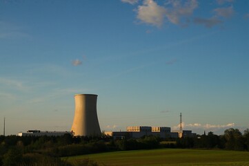 Fototapeta premium Nuclear cooling tower and power plant under a clear blue sky
