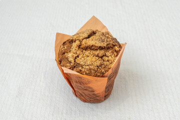 Apple and cinnamon muffin with caramelized apple pieces inside, topped with oat crumble and a scoop...