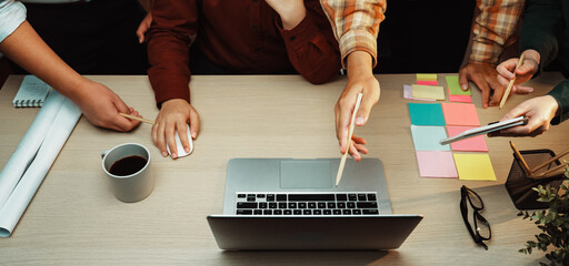 A dynamic collaborative workspace featuring laptops, colorful sticky notes, and hands engaged in planning and discussion around a modern office table. SACTR