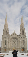 Fototapeta premium Female tourist admiring the Basilica of Sainte-Anne-de-Beaupré in winter snow, Quebec, Canada.