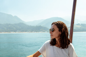 Woman enjoying the view of Angra dos Reis while traveling on a boat near Praia Grande in Brazil during a sunny day