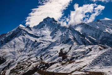 Tilicho Peak and surrounding alpine ridges near Muktinath, Nepal. Dramatic Himalayan mountain scene with sharp rock formations, snow-covered slopes, and deep blue sky, 