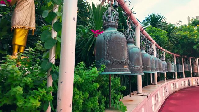 Bronze temple bells hanging in row in Wat Saket Buddhist temple, Ornate thai wind bells along railing 4k
