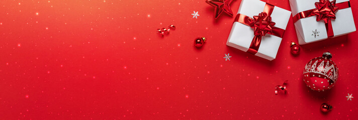 Christmas gifts with red glitter decorations on red background with bokeh. Merry Christmas and Happy New Year greeting card. Xmas and Winter holidays. Christmas wide banner, top view