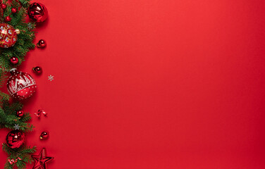 Merry Christmas and Happy New Year greeting card. Christmas tree branches with red glitter decorations on red background with bokeh. Xmas and Winter holidays. Christmas background, top view