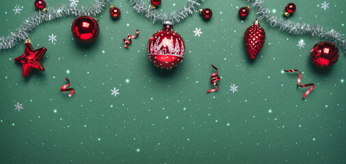 Christmas red glitter decorations with silver garland on green background. Merry Christmas and Happy New Year greeting card. Xmas and winter holidays, Christmas wide banner, top view