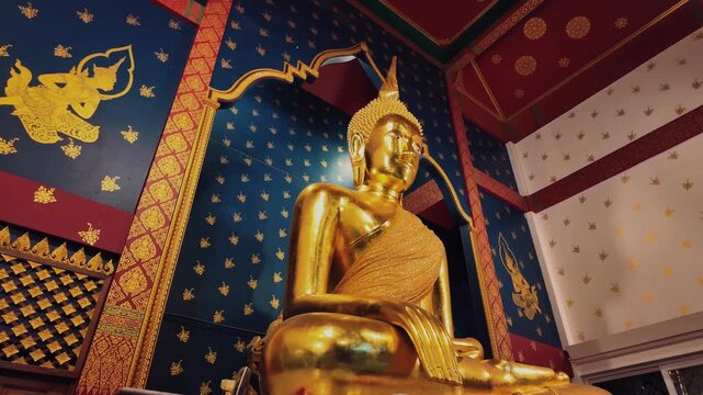 Golden Buddha statue inside Wat Saket temple with ornate interior, Lit gold Buddhism shrine with blue wall decoration in Thai temple in Bangkok 4k