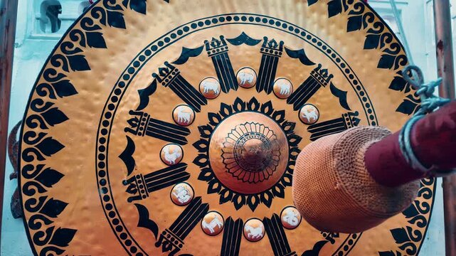 Person hand strike golden gong by mallet in Wat Saket Buddhist temple, Ritual Thai gong hit by man, first person view 4k