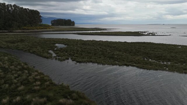 Aerial Low View of Coastal Bay with Grassy Islands under Dramatic Clouds