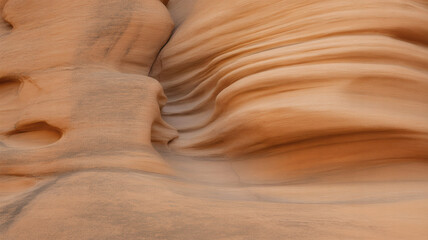 Abstract texture of smooth, wind-carved sandstone formations showcasing beautiful natural wavy patterns and rich desert tones in a close-up geological study