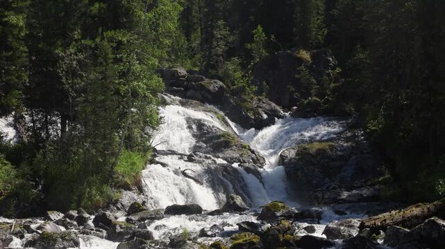 A large waterfall in the Altai Mountains, falling into the valley from high cliffs