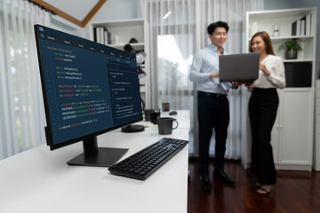 Running on coding programming intelligence system on computer screen with blurry IT developers standing with laptop at corner modern office, talking online software development information. Infobahn.