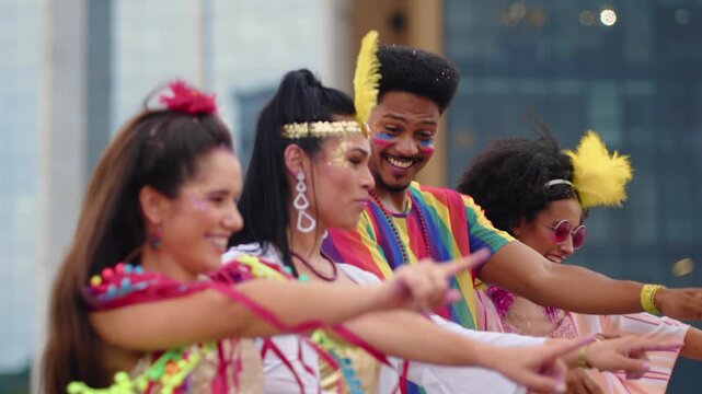 Joyful group of friends performing choreography at Brazilian Carnival celebration. Happy people in colorful outfits dancing together during a traditional street festival