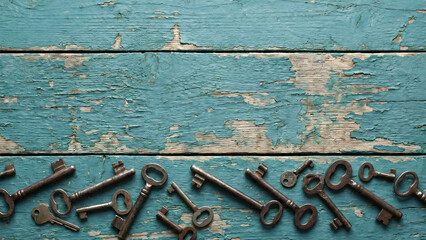 Row of antique skeleton keys on weathered blue wooden texture with copy space