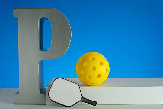 P is for Pickleball.  Large letter "P" with yellow Pickleball and small paddle on blue background