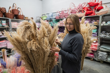 A Caucasian woman buys dried flowers at a home decor store.
