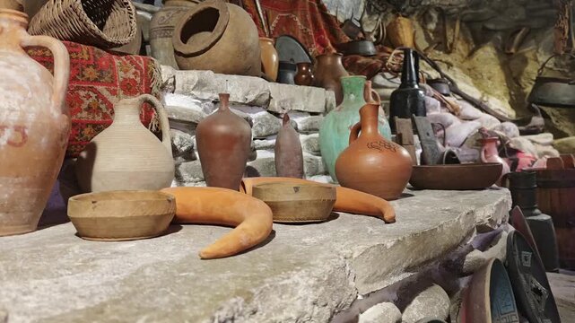 Antique assortment of Georgian ceramic pitchers, pottery, and classic wine making tools showcased in a charming stone cellar or marani