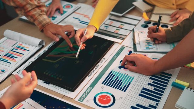 Diverse team members engage in data analysis and discussion, utilizing charts and graphs on a modern workspace to formulate strategic plans and drive insights. SACTR