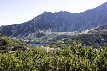Mountain lake surface reflecting light beneath steep rocky slopes in Valley of Five Polish Ponds