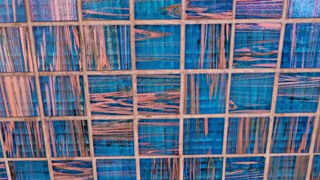 A close-up of a blue, grid-patterned surface with streaked brush-like marks and scratches, creating an abstract, textured pattern suitable for background, overlay, or design elements.